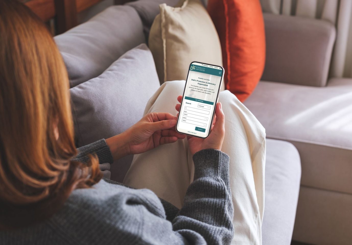 Woman on couch looking at Disability Law Center Mobile Mockup