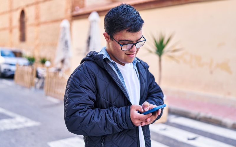 A young man uses a mobile phone to view Disability Rights Arizona's website