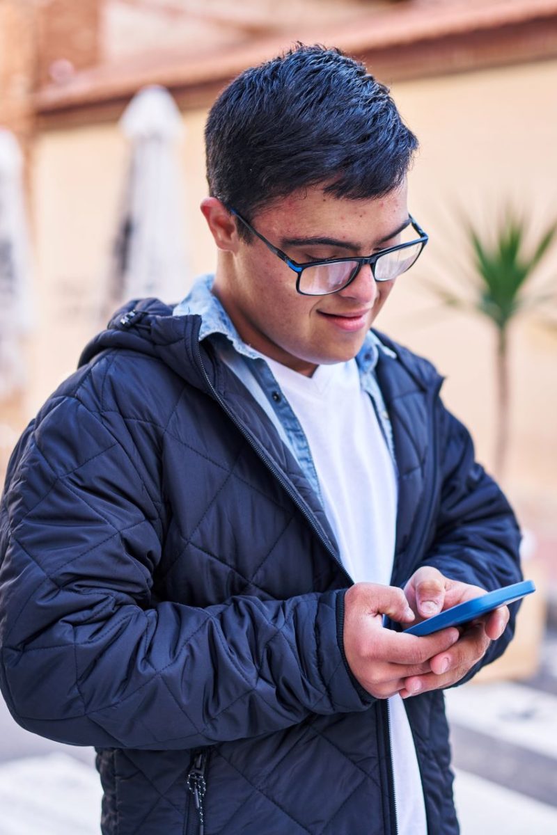 A young man uses a mobile phone to view Disability Rights Arizona's website